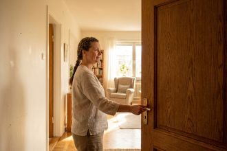 Femme choisissant une porte battante en bois chêne dans un couloir intérieur chaleureux